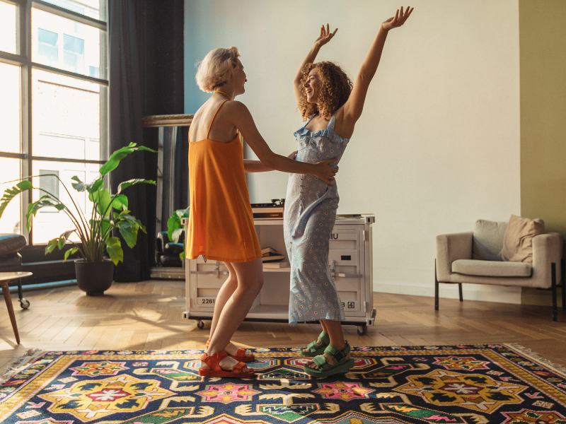 Two women dance and laugh at home