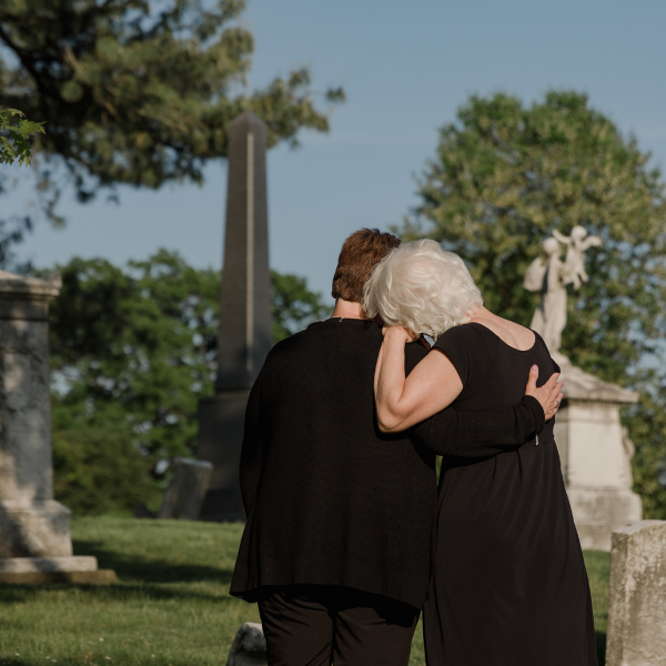 Two women mourn at the grave of a loved one