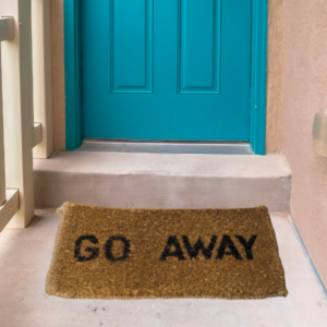 A blue door with a welcome mat outside with the words 'Go Away' wrtitten on it