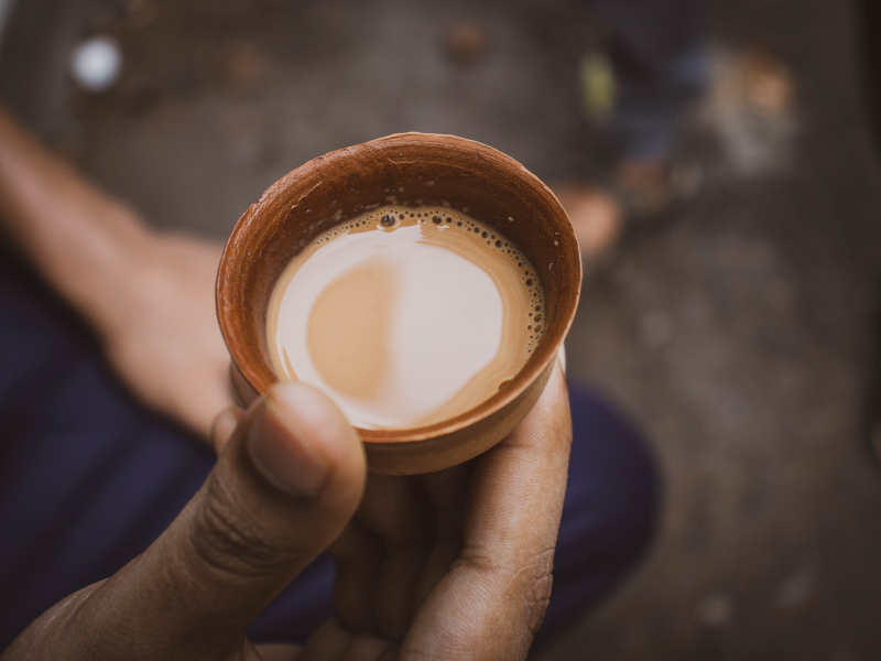 A hand holds a small cup of hot tea