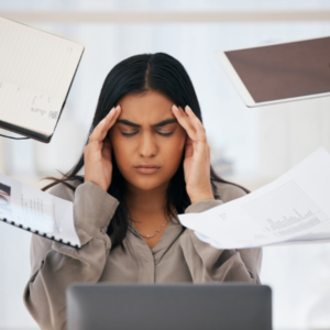 Woman looking stressed surrounded by papers and notebooks