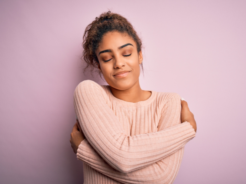 A woman looks relieved as she gives herself a warm embrace.